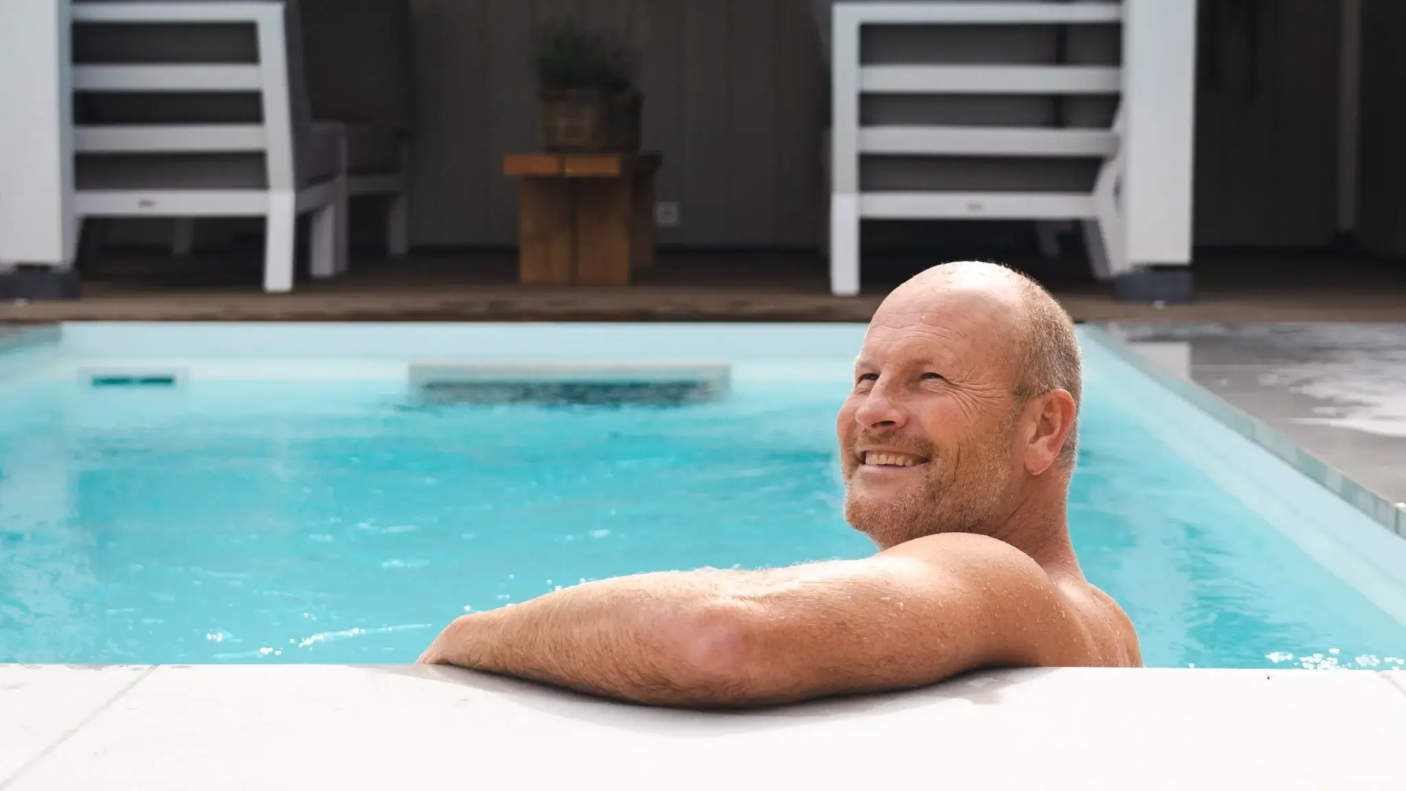 Влияние плавания на тело - мужчина улыбается в бассейне